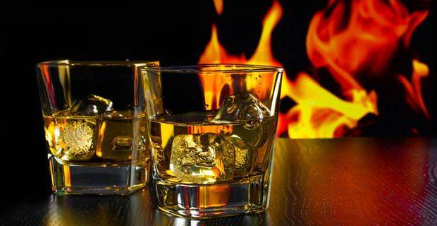 Glasses of Malt Whisky over Ice infant of Log Fire